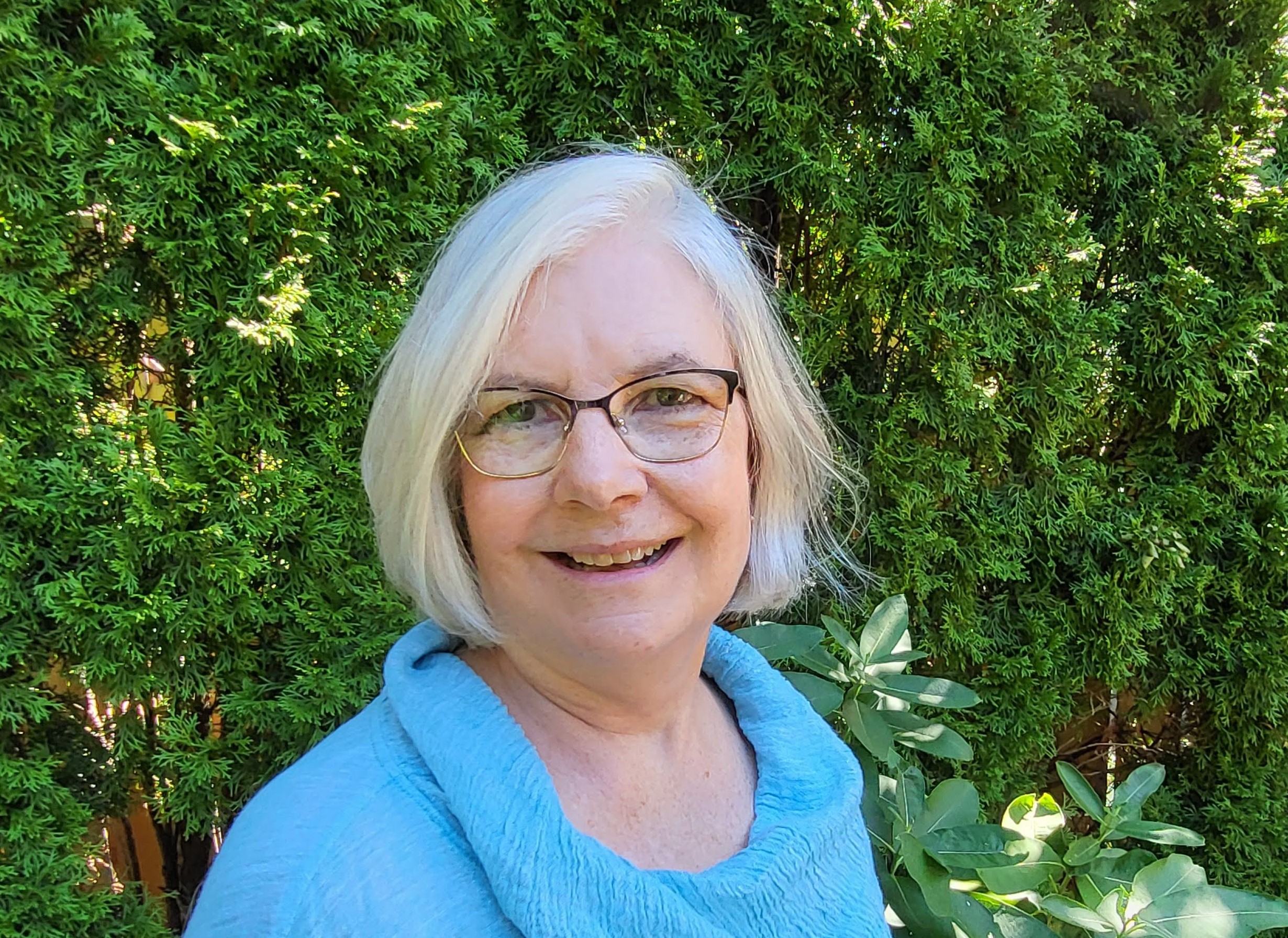 Dr. Horton stands in front of a hedge and smiles at the camera